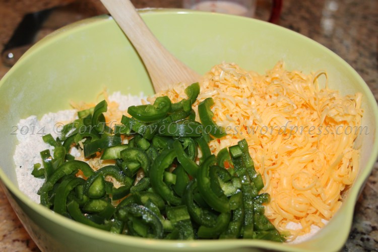 Add the jalapeños and shredded cheddar to the dry ingredients and stir with a wooden spoon. Break up any large chunks of cheese.